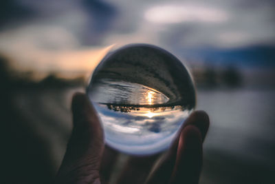 Close-up of hand holding crystal ball against blurred background