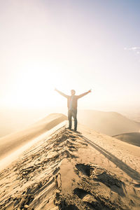 Man with arms outstretched standing on beach