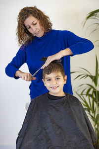 Funny boy getting haircut at home with scissors