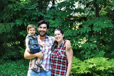 Portrait of happy family standing against trees