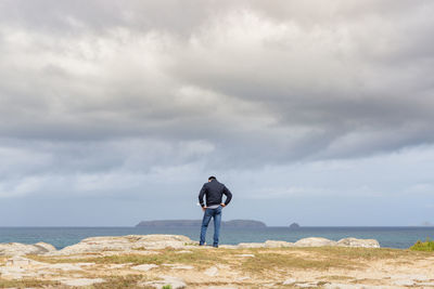 Rear view of man looking at sea against sky