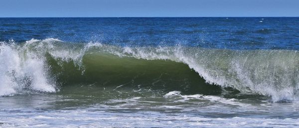 Waves splashing on sea against sky