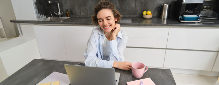 Side view of young woman using laptop while sitting at home