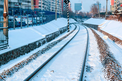 Snow covered railroad tracks in city during winter