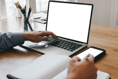 Midsection of man using laptop on table