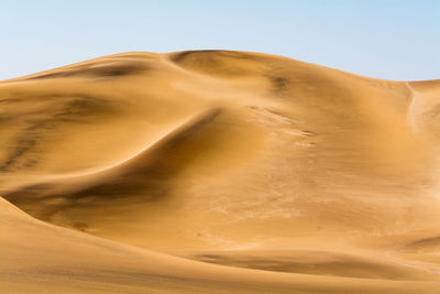 Sand dunes in desert against blue sky