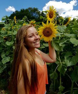 Smiling woman standing by sunflowers