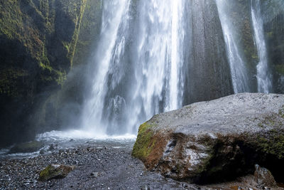 Scenic cascades of gljufrafoss by rock flowing from mountain hidden in cliffs