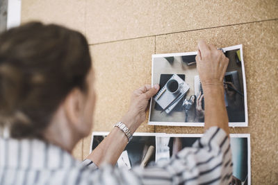 Rear view of senior businesswoman pinning photograph on bulletin board in portable office truck