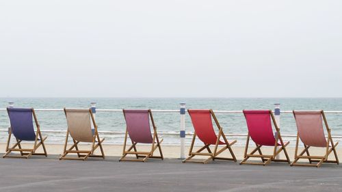 Lounge chairs arranged at promenade against clear sky