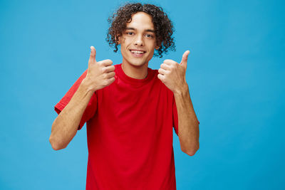 Portrait of smiling young man against blue background