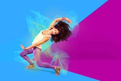Digital composite image of happy woman dancing against colored background 