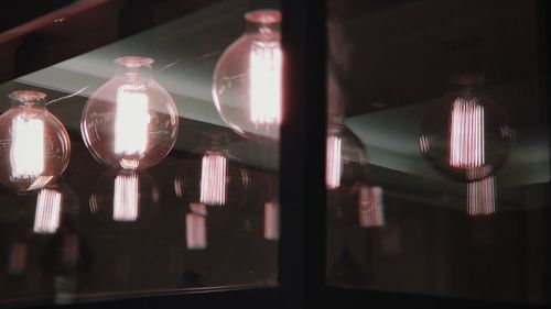 Low angle view of illuminated light bulbs hanging from ceiling