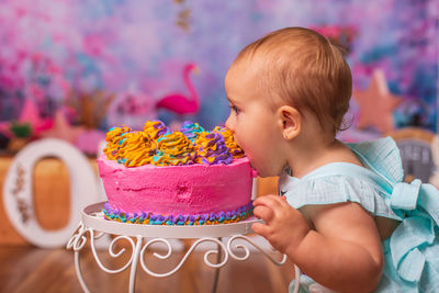 Portrait of cute baby eating cake without hands