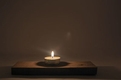 Close-up of illuminated tea light candles on table in darkroom