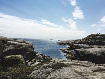 Scenic view of rocky coastline against sky on sunny day