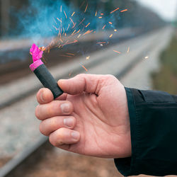 Close-up of man igniting firecracker outdoors