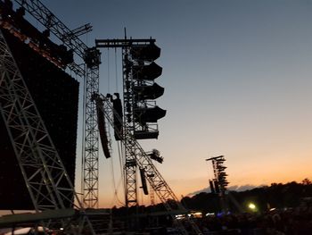 Low angle view of cranes at construction site during sunset