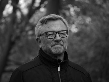 Close-up of senior man wearing eyeglasses against trees