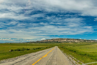 Road amidst field against sky