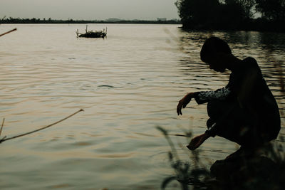 Silhouette man sitting in lake