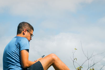 Man sitting on plant against sky