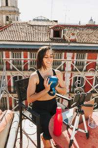 Young sporty fit woman coach doing online lessons through video call on her mobile phone 