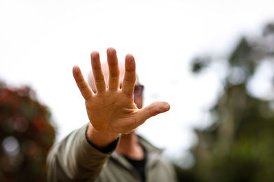 Mature man gesturing stop sign against sky