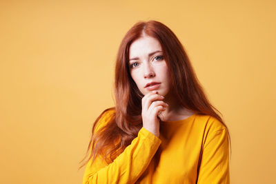 Portrait of young woman against yellow background