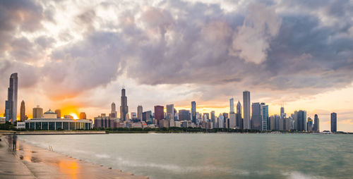 Panoramic view of sea and buildings against sky during sunset