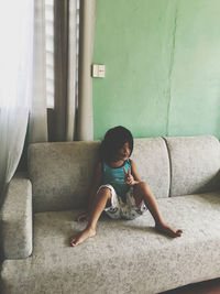 Young woman sitting on sofa at home