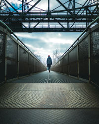 Rear view of person walking on footbridge