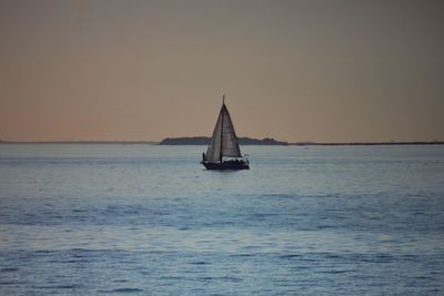 Sailboat sailing on sea against sky during sunset