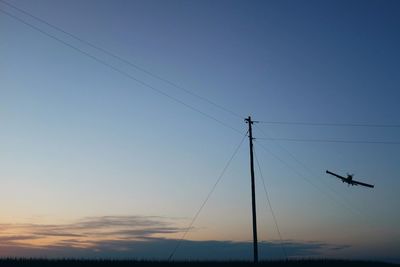 Low angle view of crop sprayer over field against sky during sunset