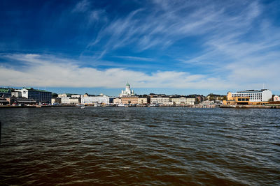 Buildings at waterfront against cloudy sky