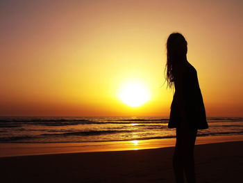 Silhouette man standing at beach during sunset