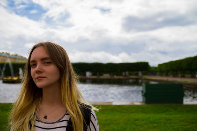 Portrait of young woman against river