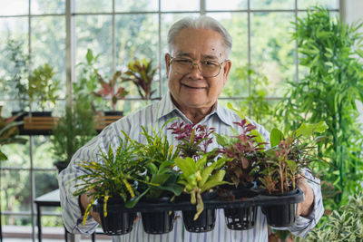 Portrait of smiling young man holding potted plant