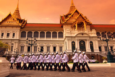 Army soldiers marching by historic building during sunset