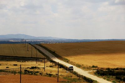 Road amidst field against sky