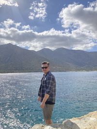 Young man standing on lake against sky