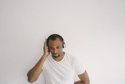 Man wearing headphones sitting against white background