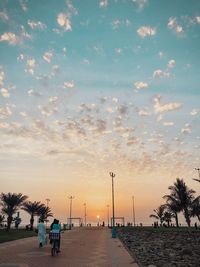 People on road against sky during sunset