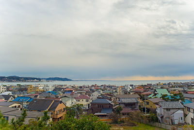 Town by sea against cloudy sky