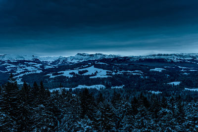 Scenic view of snow covered mountains against blue sky