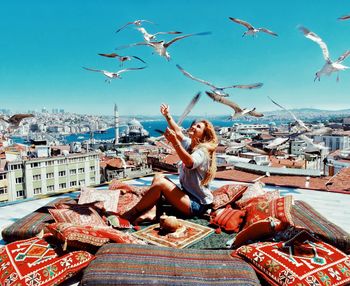 Woman flying by buildings in city against sky