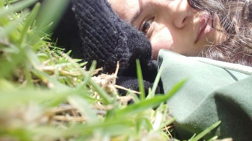 Close-up portrait of young woman relaxing on grassy field