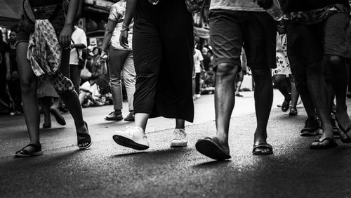 Low section of people walking on street in city