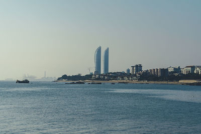 Sea and buildings against clear sky