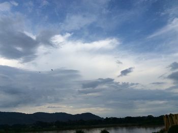 Silhouette birds flying over lake against sky during sunset